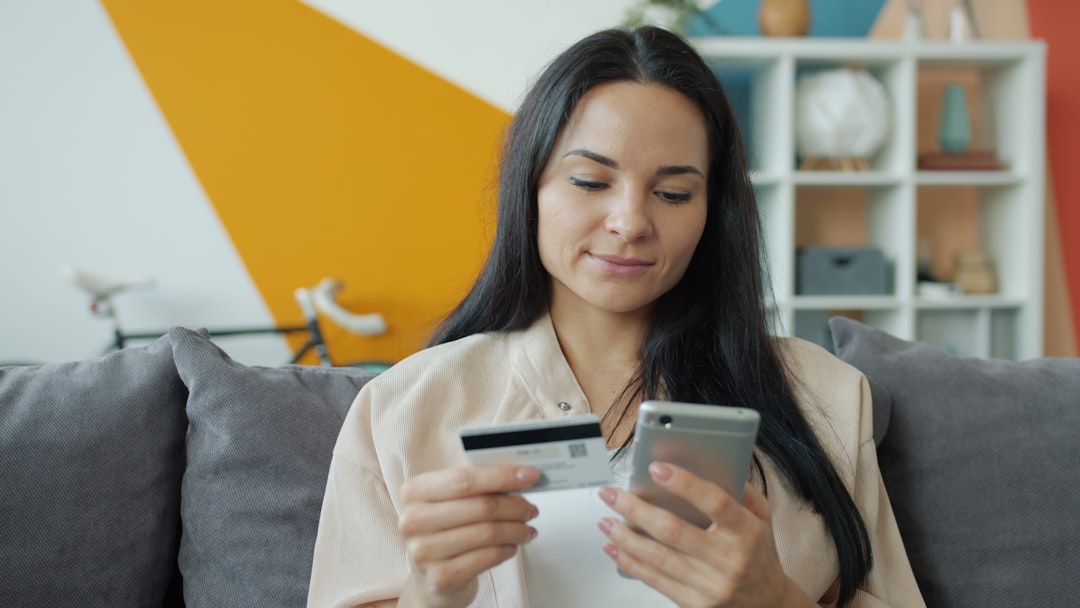 Woman holding credit card and phone for online shopping.