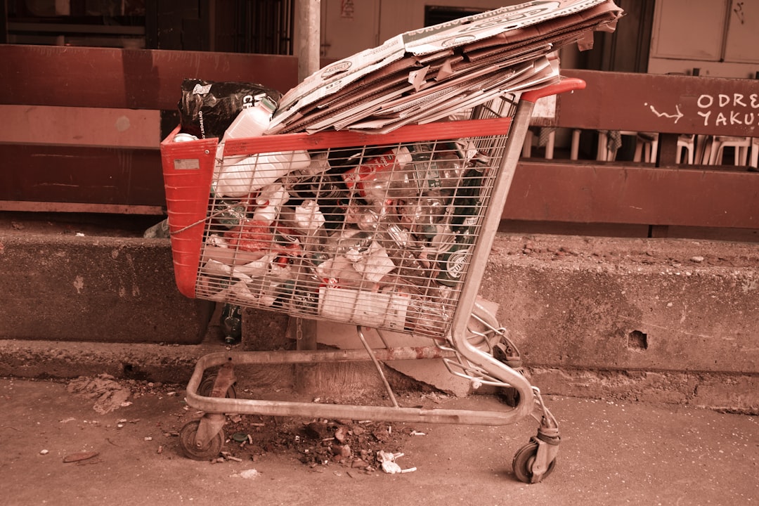 A shopping cart filled with lots of items sitting on the side of a road