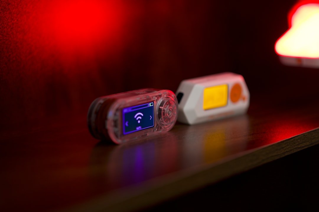 Two small electronic devices on a dark surface.