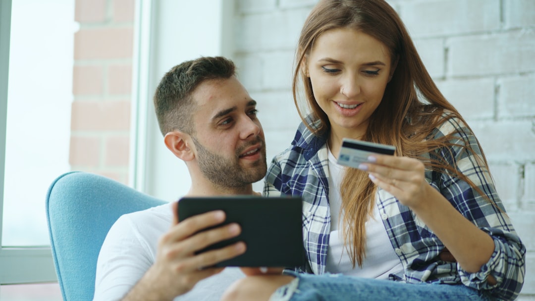 Couple using tablet and credit card for online shopping.