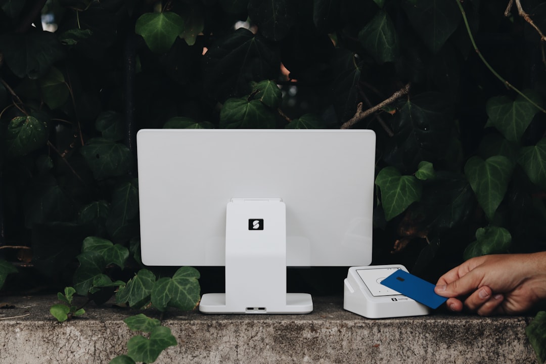 A person holding a blue and white object near a computer