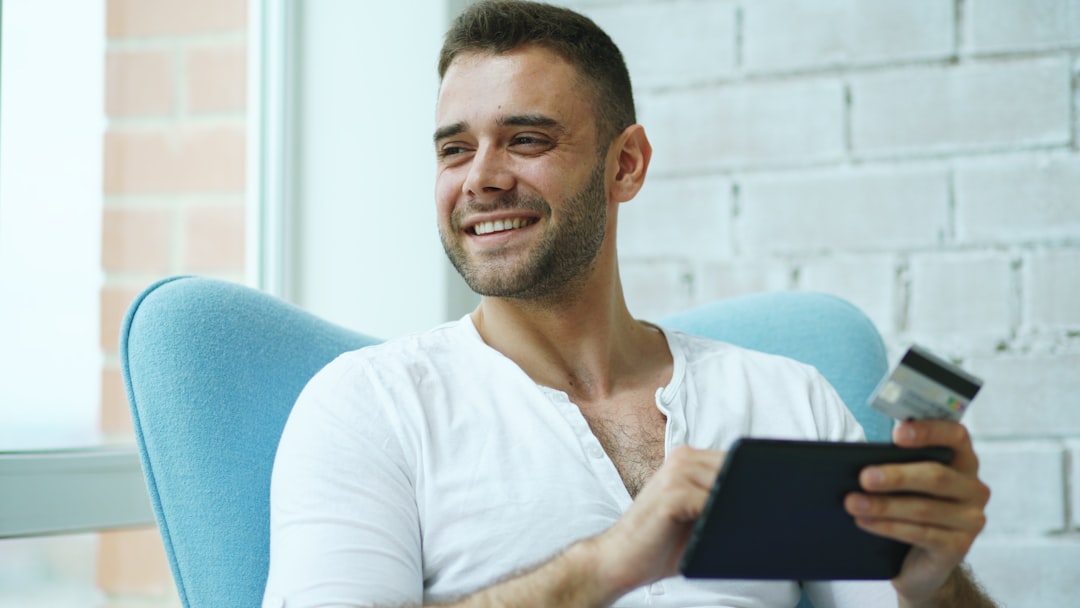 Man smiling while using tablet and credit card