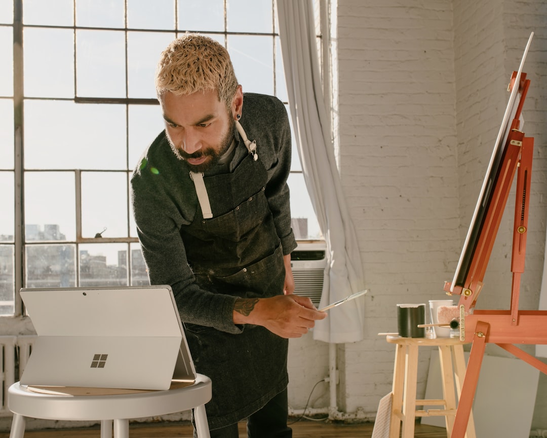a man is painting a picture on a laptop