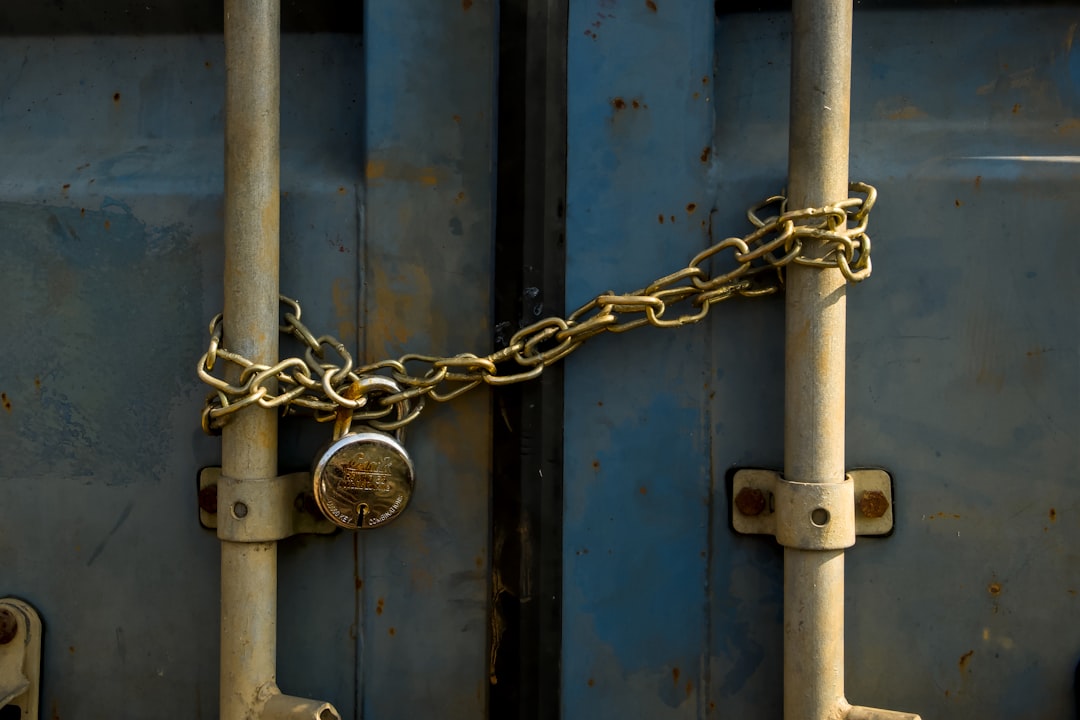 A rusty padlock and chain securing blue doors