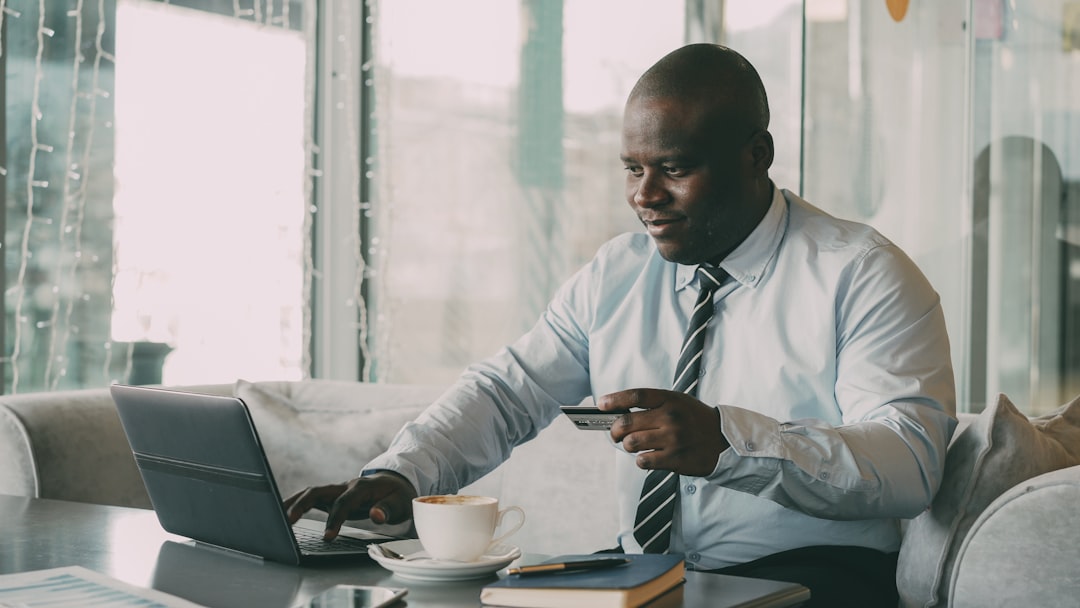 Man in shirt and tie using laptop and credit card.