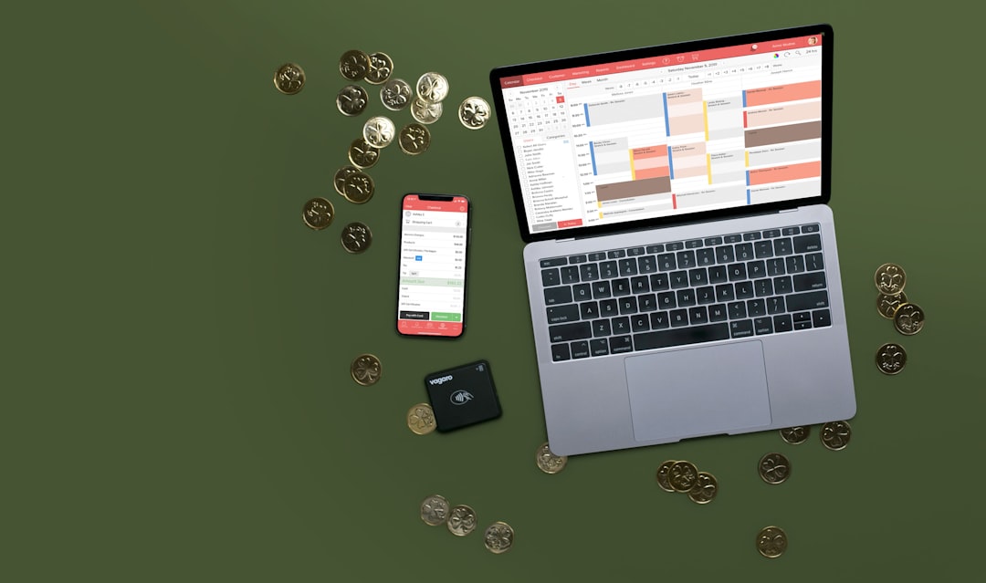 Laptop, phone, and coins on a green surface