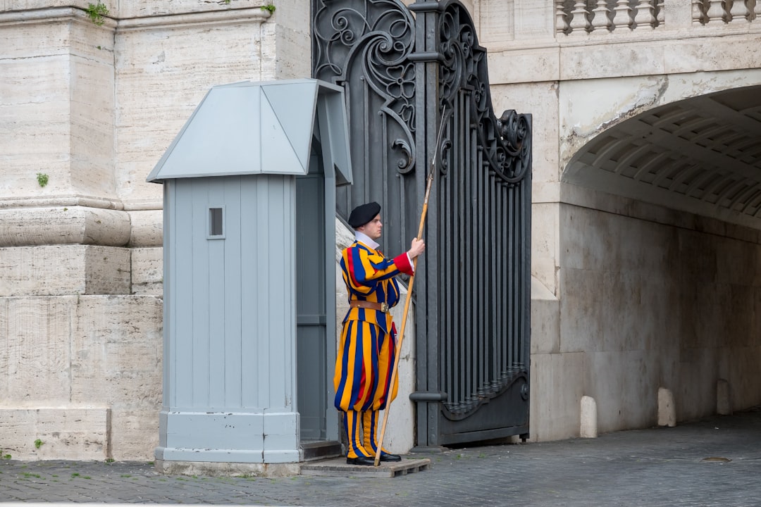 man in yellow and black traditional dress standing on sidewalk during daytime